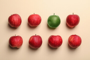 Individuality, uniqueness, different. Green apple among red ones on beige background, flat lay