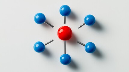 One red pin stands out among five blue pins arranged in a circle on a white background. This shows teamwork, being different, and leading.
