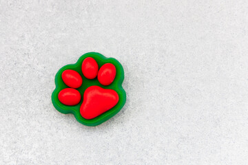 Bright red paw print shaped toy sits on a light gray surface