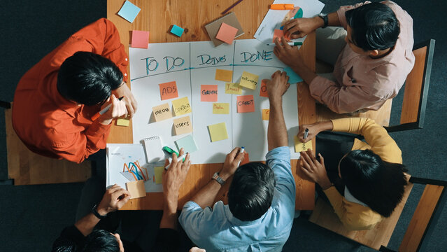 Top view of people writing and making scrum task board while writing marketing and planning strategy at colorful sticky notes. Smart team manage work performance by using kanaban board. Convocation.
