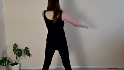 pregnant girl in black sports overalls standing back and doing twists, doing fitness exercises 