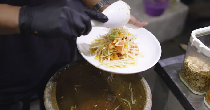 local street stall preparing Som Tum or Thai Papaya Salad, Asian street food, famous traditional dish. Green papaya salad put pickled peanut and Pickled fish. Asian food daily style.