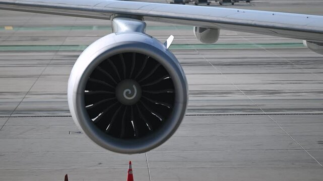 Jet Engine Spinning on Parked Commercial Aircraft at Airport Apron During Taxiway Activity, Close-Up View