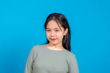 Obraz premium Young Asian woman with a subtle smile and raised eyebrow giving a confident, slightly sassy look to the camera. Expressive pose ideal for lifestyle, attitude, or branding campaigns.