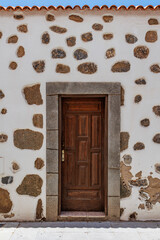 Rustic wooden door in stone wall facade, Old wooden door set in a whitewashed wall with exposed natural stones.