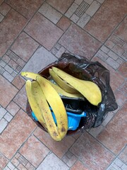 Top view of a trash bin filled with plastic food boxes and covered with banana peels as a waste sorting concept and environmental conservation