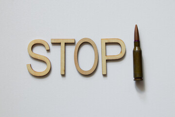The word stop laid out in wooden letters, with a bullet on a white background, stop war