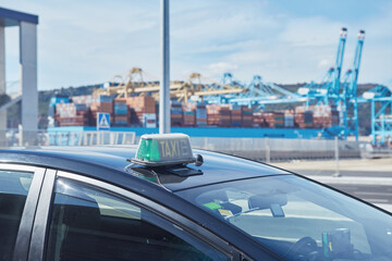 Spanish Barcelona Taxi sign close-up view in the port terminal with the docked container ship in...