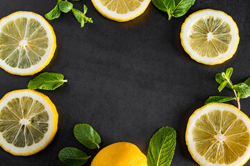 Fresh juicy lemon slices on black background. Cocktail ingredient - mint leaves and lemon. Food...