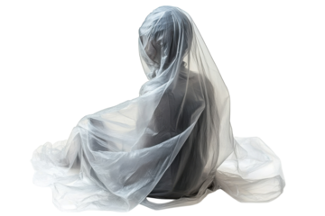 Serene figure shrouded in sheer grey fabric sitting thoughtfully in soft light against a white