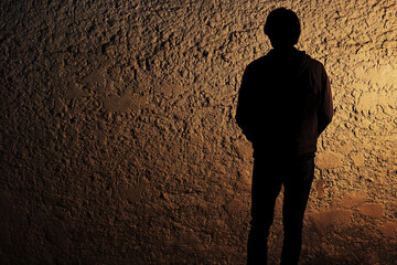 Person standing quietly against a textured wall at dusk Generative AI