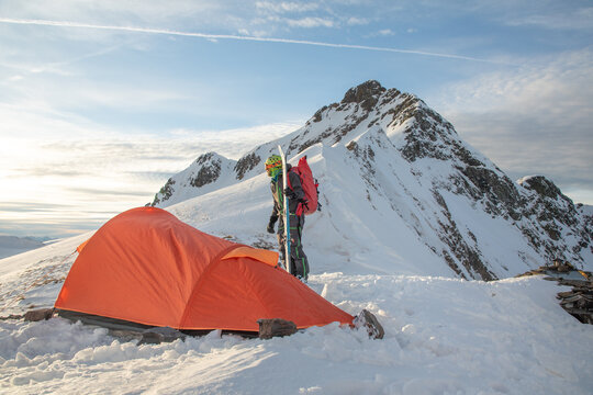 Adventurous ski tourer with tent in snowy mountain landscape