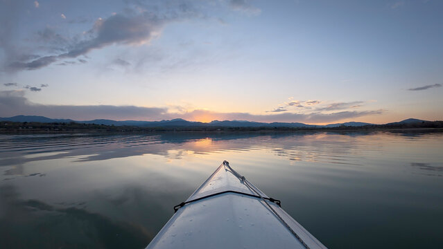 sunset kayaking or canoeing on a calm lake in the foothills of the Rocky Mountains in Colorado - POV paddler perspective
