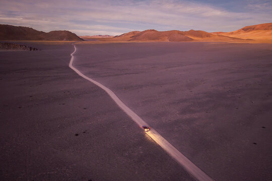 Car on a long desert road at dawn in the argentine Puna