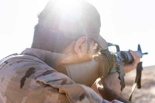 Soldier Aiming Rifle with Sunburst Effect in Desert Setting
