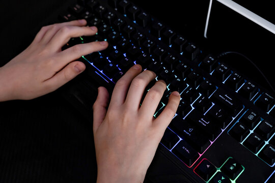 Teenage gamer’s hands on illuminated keyboard - Powered by Adobe