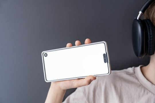 Teen Holding Smartphone with Blank White Screen and Headphones