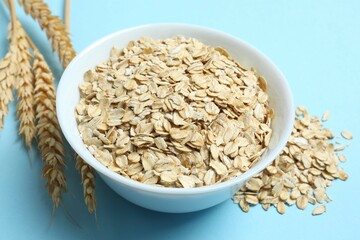 Composition with oatmeal flakes on blue background. Cooking breakfast
