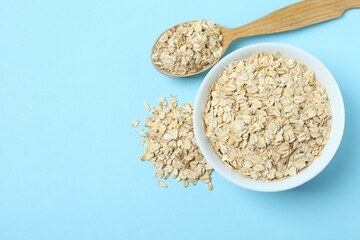 Composition with oatmeal flakes on blue background. Cooking breakfast