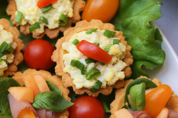Mini tartlets with egg salad. Savory pastry snack. Fresh tomato and green onion. Appetizer on lettuce. Colorful Easter food. Homemade tartlet. Party finger food. Traditional holiday celebration.
