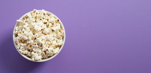 Delicious popcorn in a bowl on a colored background