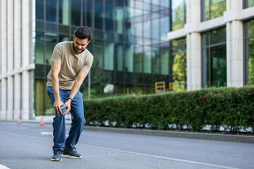 An Indian young man is busy running and exercising outside, injured, standing crooked in pain and...