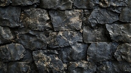 Dark, rough-hewn stone wall texture; irregular, dark grey blocks closely fitted together