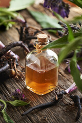 A bottle of  herbal tincture with fresh knitbone or comfrey root