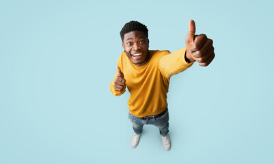 Top view of joyful handsome african american millennial guy in nice outfit showing thumb up and...