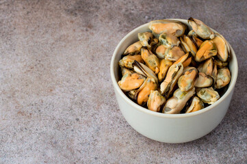 Cleaned boiled mussels in a bowl on a dark background, horizontal