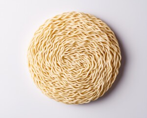 Obraz premium A round, uncooked bundle of instant ramen noodles on a plain white background.