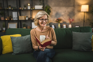 Obraz premium One woman mature caucasian female read book at home wear eyeglasses