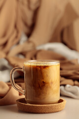 Glass cup of latte on a beige background.