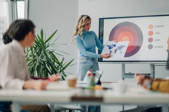Young businesswoman showing global market share during a presentation to colleagues in a meeting room