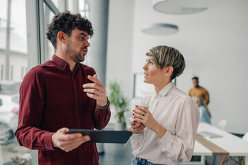 Business colleagues discussing work using tablet in modern office
