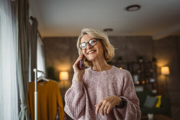 One mature blonde woman stand at home use mobile phone talk