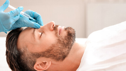 Side view of middle-aged man getting beauty injection in nose at aesthetic clinic. Plastic surgeon...
