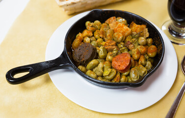 Traditional Catalan tapa of faba beans stewed with morcilla, chorizo and bacon served on frypan