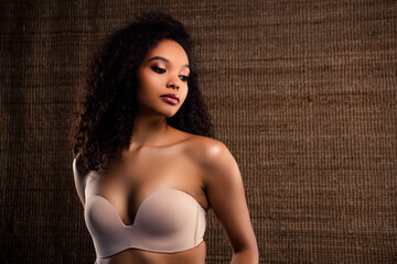 Elegant young woman with natural beauty showcasing makeup and style against a textured brown...