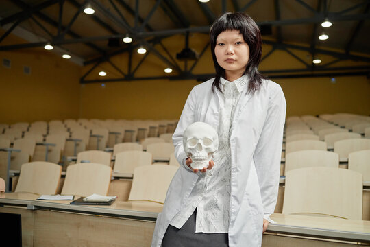 Portrait of smiling young Black male med student sitting at desk and writing in clipboard during college lecture in university classroom