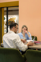 Obraz premium Two professionals collaborating in an office environment, reviewing documents and discussing ideas.