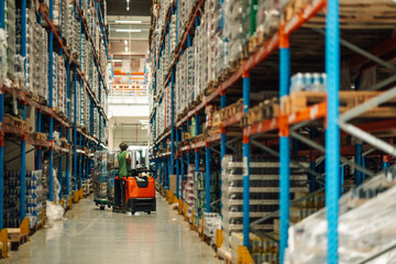 Warehouse worker transporting goods using an electric pallet jack