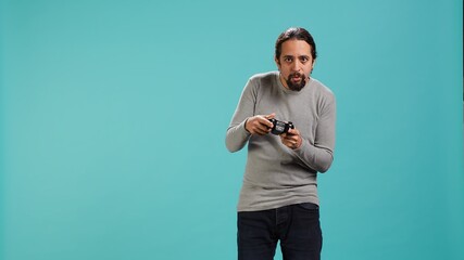 Portrait of man playing videogames holding controller, isolated over studio background. Gamer...