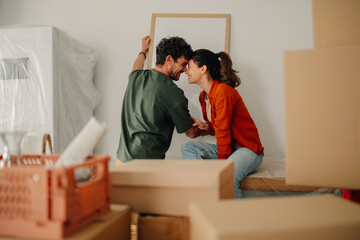 Happy couple hanging a picture frame in new home while moving in
