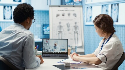 Physician entering a video call with specialist to discuss diagnostic report, asking the expert for...