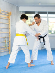 Obraz premium Adult man and teenage boy in kimono training judo fighting techniques