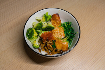 Fototapeta premium A rice bowl topped with grilled salmon, broccoli, mushroom, fish roe, and seaweed.
