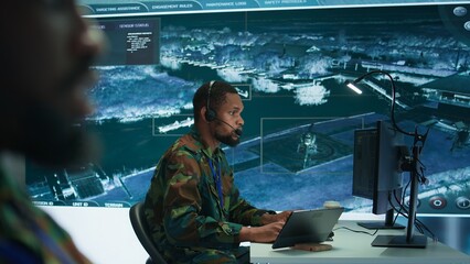 Soldiers in a modern command center analyze live data from cctv radar sources, satellite feeds and...