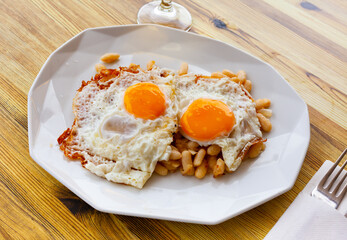 Appetizing fried eggs with stewed white beans. Traditional Catalan breakfast