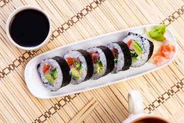 Traditional thick sushi roll futomaki filled with salmon, tuna, avocado, surimi and cucumber